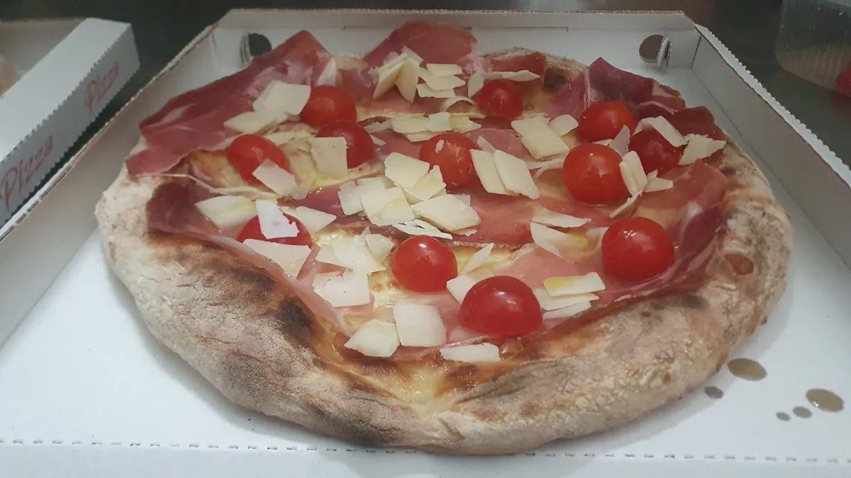 Pizza con crudo, scaglie di grana e pomodorini